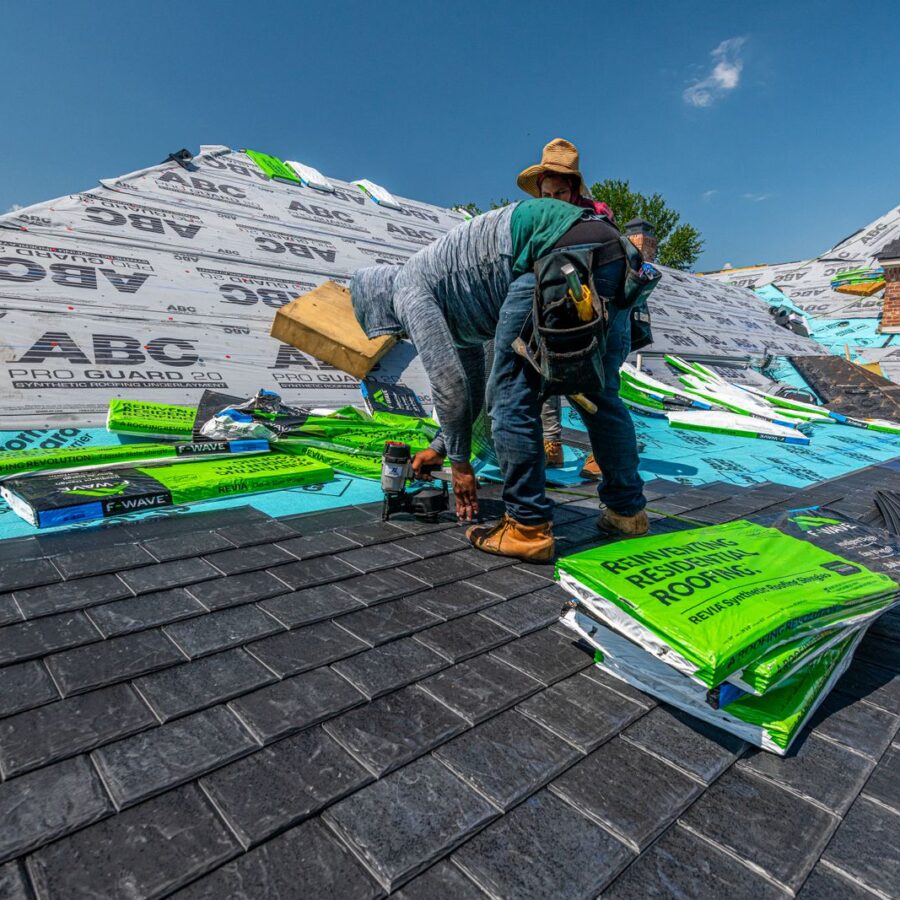 Roofing crew installing synthetic slate on a brick home in Fort Worth, Texas